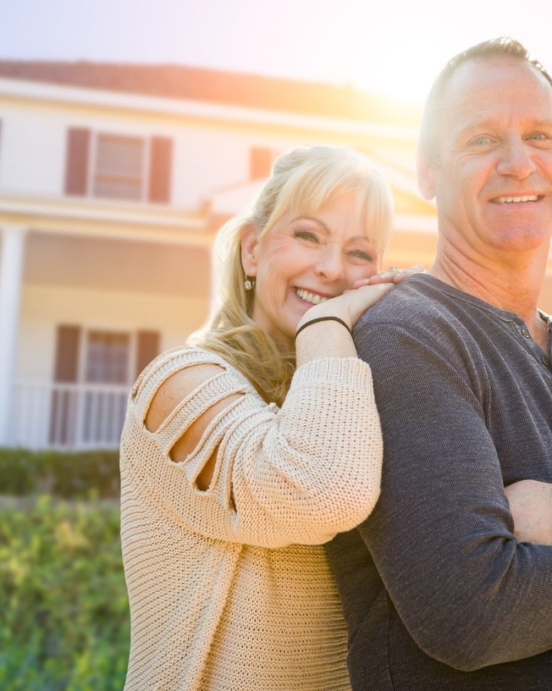 Attractive Middle-aged Couple In Front Of Their House.